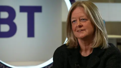Allison Kirkby sits in front of a BT logo