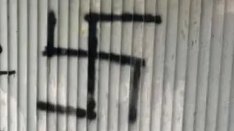 LDRS A large black swastika crudely spray painted onto a corrugated wall
