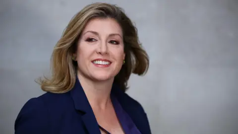 PA Media Penny Mordaunt with a blow-dry wearing a purple jacket